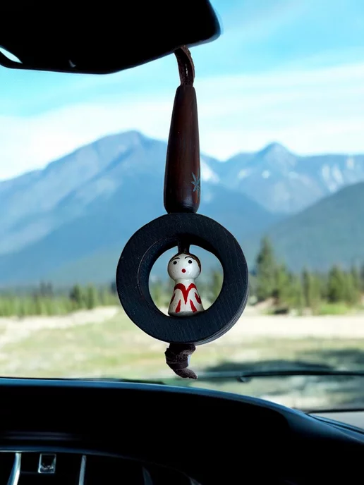 человек за рулем, на зеркале висит амулет